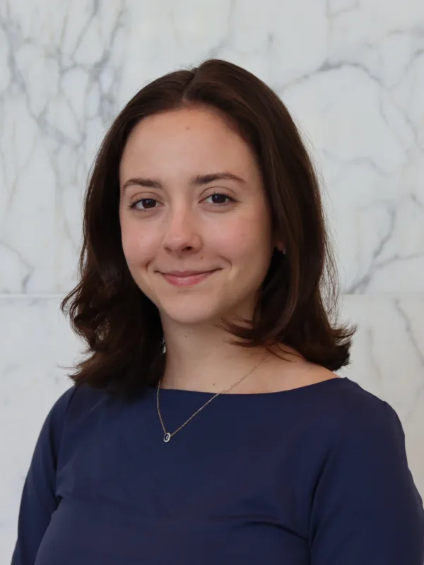 Pauline in a dark blue top in front of a white marble effect wall
