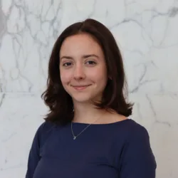 Pauline in a dark blue top in front of a white marble effect wall