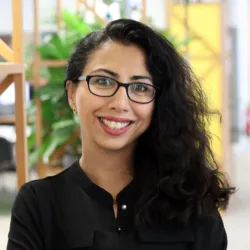 Roxana smiling to camera stood in an office space