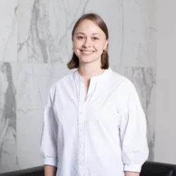 Sarah Linnell standing in front of marble background in a white shirt