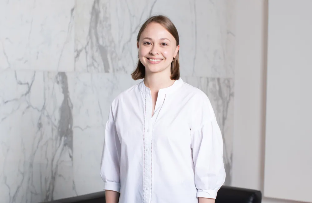 Sarah Linnell standing in front of marble background in a white shirt
