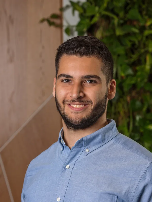 Seif wearing a blue shirt standing against a blurred background