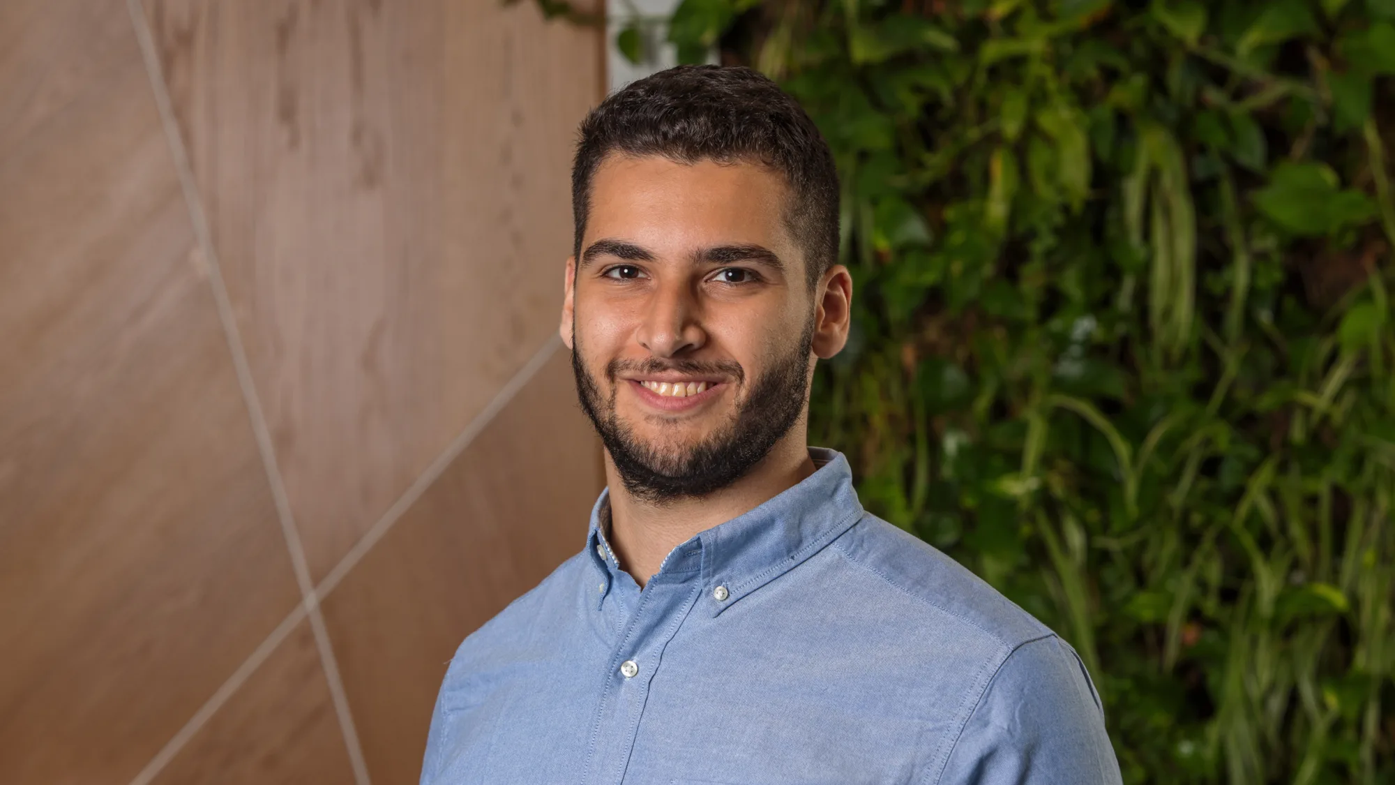 Seif wearing a blue shirt standing against a blurred background