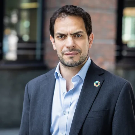 Simon Wyatt in front of office facade in a dark suit and blue shirt