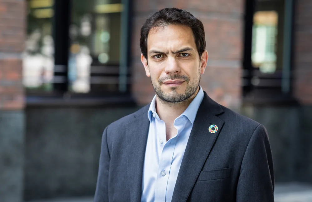 Simon Wyatt in front of office facade in a dark suit and blue shirt