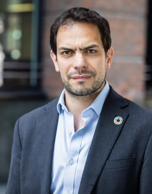 Simon Wyatt in front of office facade in a dark suit and blue shirt