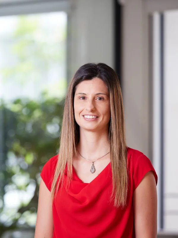 Valeria Riso smiling towards the camera in a red top against a blurred background of the London office