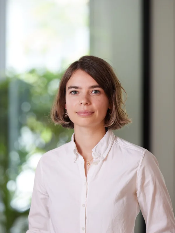 Vera Sehlstedt in a white shirt standing against a blurred background in the London office