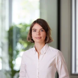 Vera Sehlstedt in a white shirt standing against a blurred background in the London office