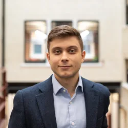 Teodor stood in the atrium in front of rust red railings and interior windows