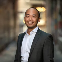 Benny Cheah in a suit and white shirt with a street background blurred