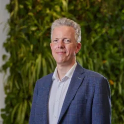 Duncan Cox stood in front of a green plant wall