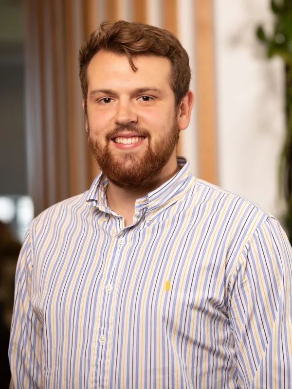 Headshot of Marko, in front of a timber and plant wall.