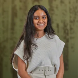 Prarthana Ravikumar in a white top with green glass background