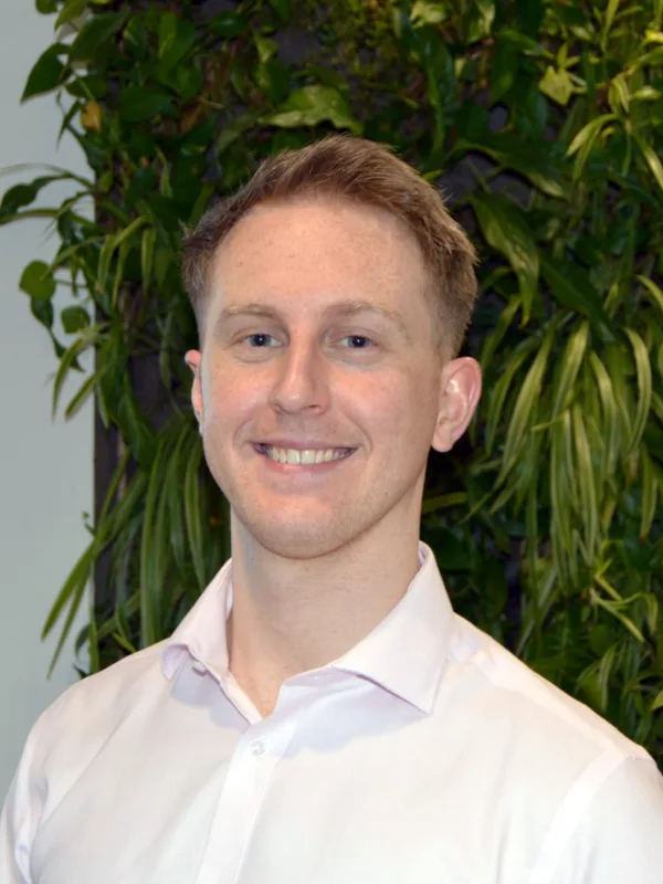 Tom in a white open collared shirt in front of a living wall