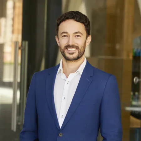 Oliver Grimaldi in suit in front of office entrance glass doors
