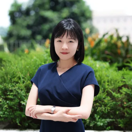 Chaoming in a navy short sleeved dress stood, arms crossed outside.