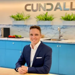 Matt sat with arms resting on a long table with a kitchen in the background and Cundall logo on the wall