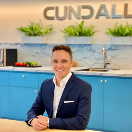 Matt sat with arms resting on a long table with a kitchen in the background and Cundall logo on the wall