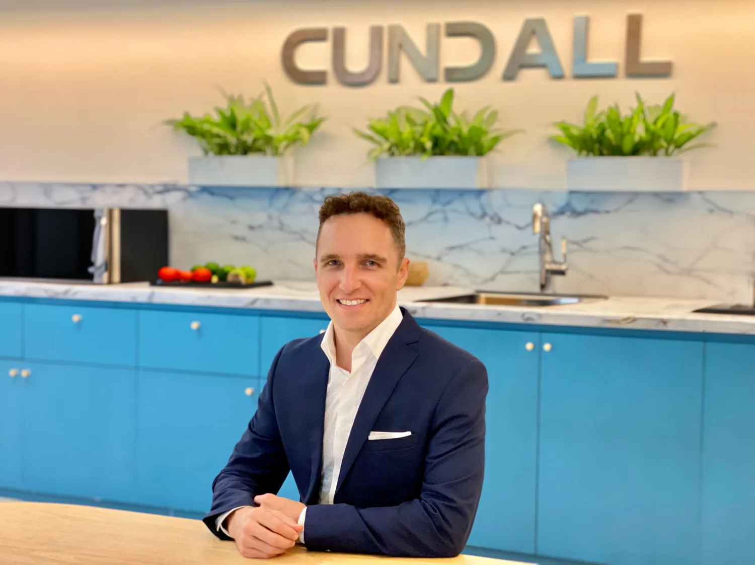 Matt sat with arms resting on a long table with a kitchen in the background and Cundall logo on the wall