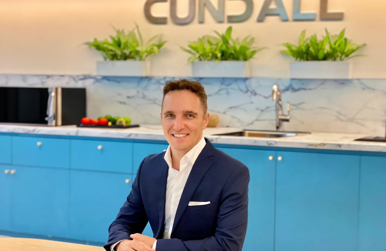 Person seated at a desk in a commercial office space with blue cabinetry and a wall displaying the Cundall logo.