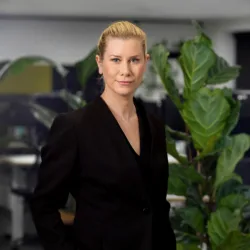 Hannah wearing suit standing in front of a plant
