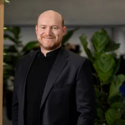 Jordan wearing a black suit standing in front of a plant