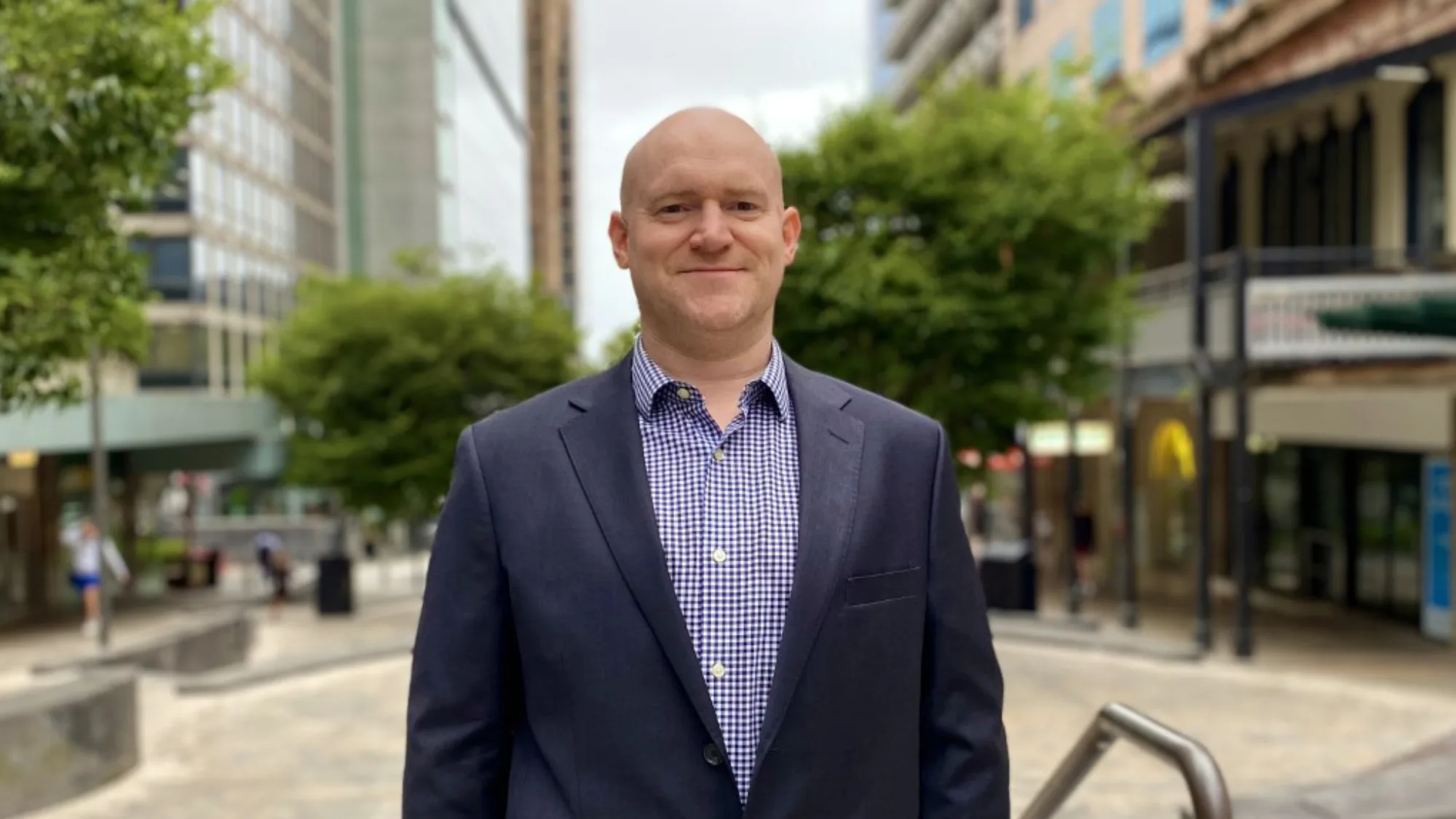 Jordan stood in a quiet street with trees and buildings in the background