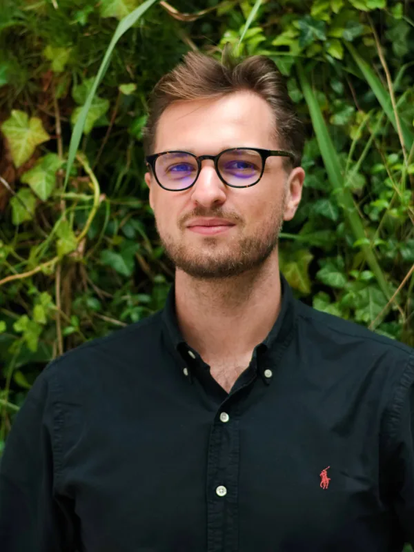 Igor in a dark open collar shirt in front of a living wall