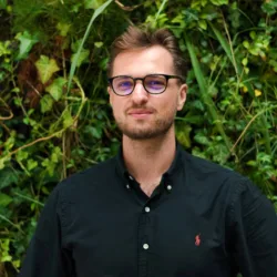 Igor in a dark open collar shirt in front of a living wall