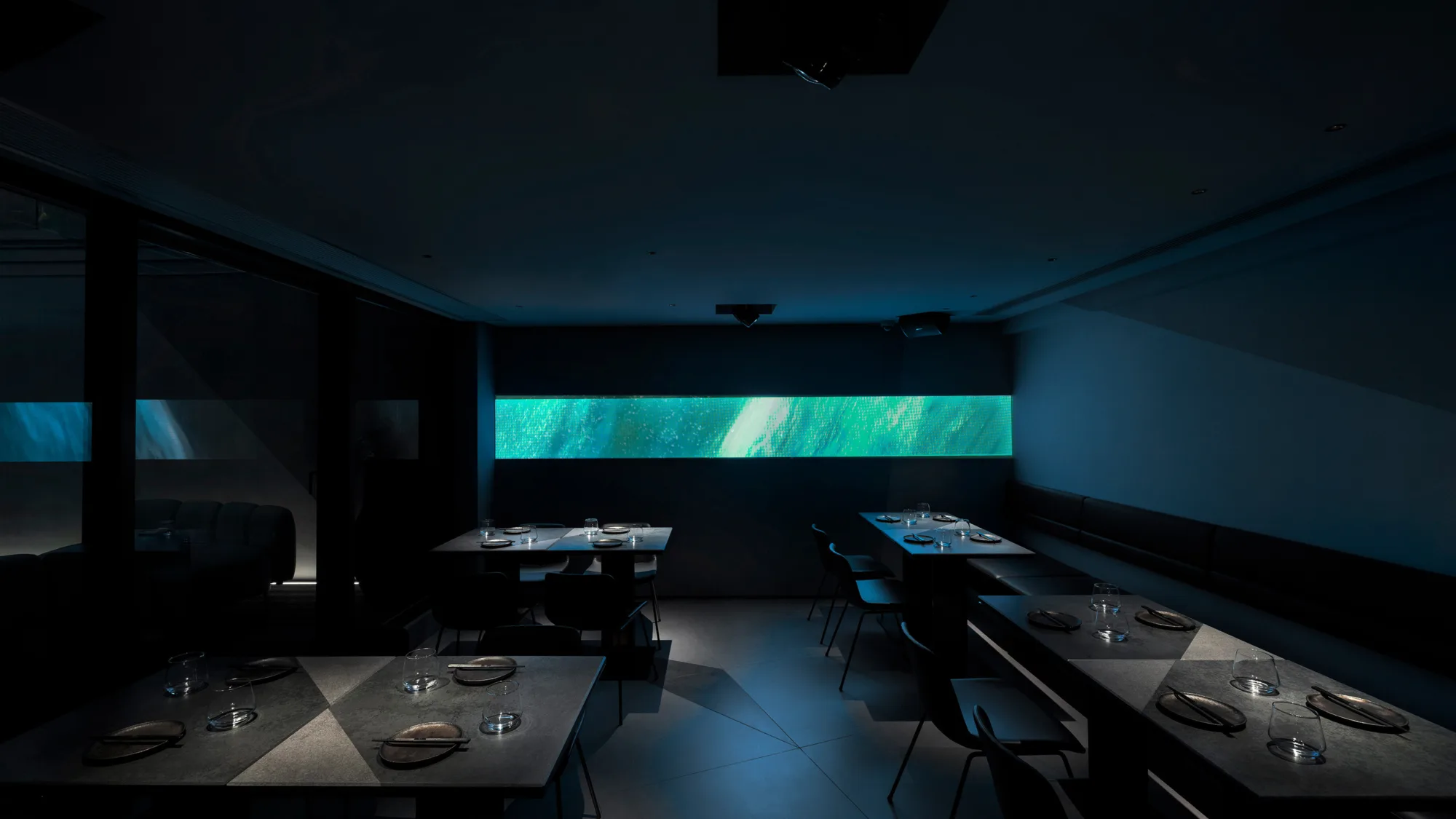AOAO main dining area with spotlights on tables with illuminated green light at the backdrop.