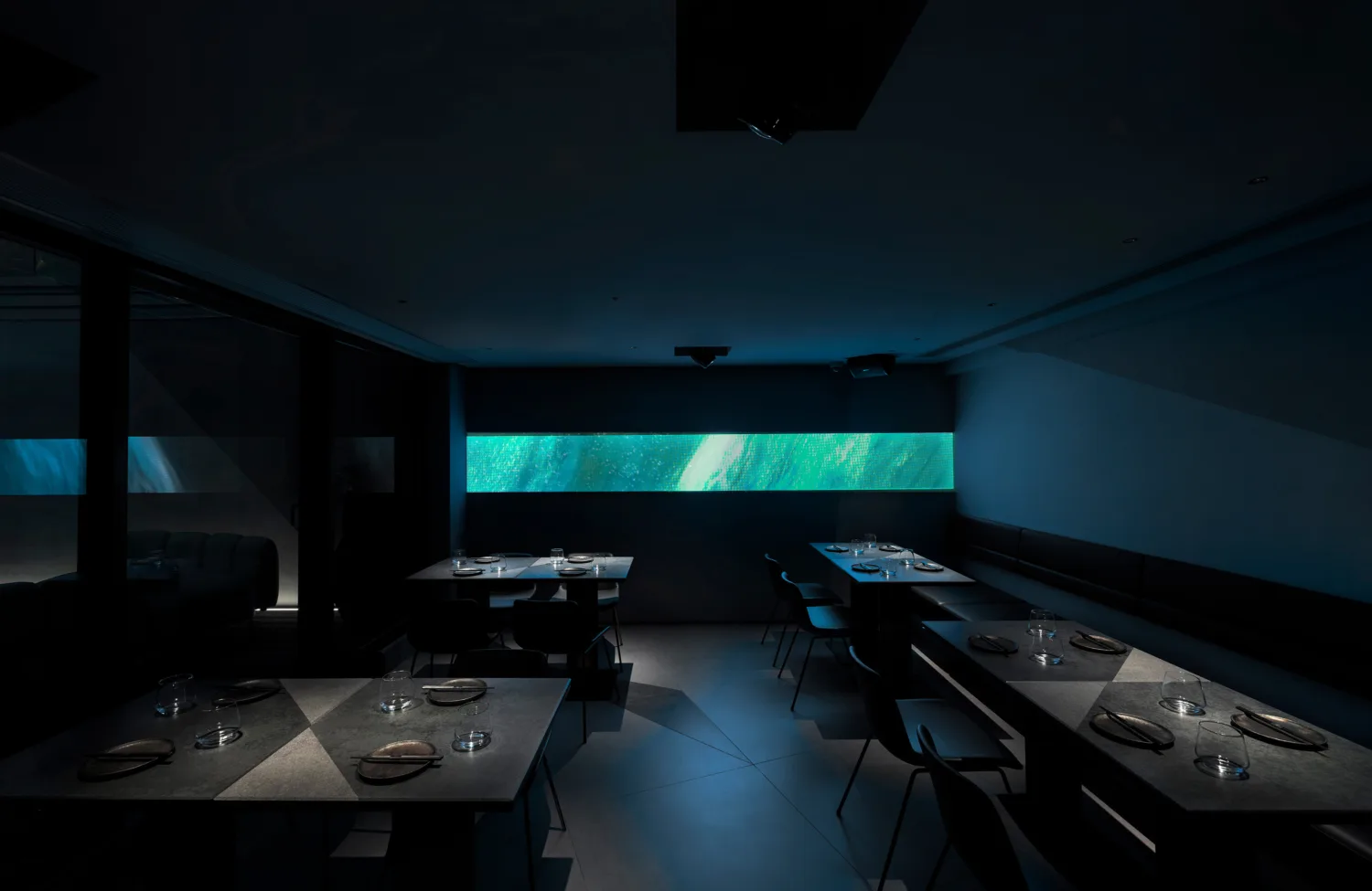 AOAO main dining area with spotlights on tables with illuminated green light at the backdrop.