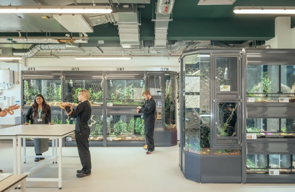 Inside the Animal Studies Centre with people holding animals and other animals behind in glass around the room.