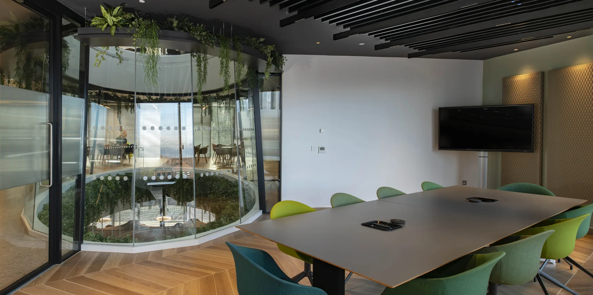 One of the meeting rooms in the office, minimalist table and chairs and a tv with a glass wall looking into the rest of the office
