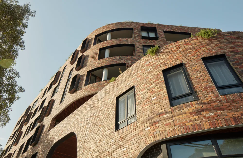 Looking up at the brick exterior with multiple windows to a blue sky