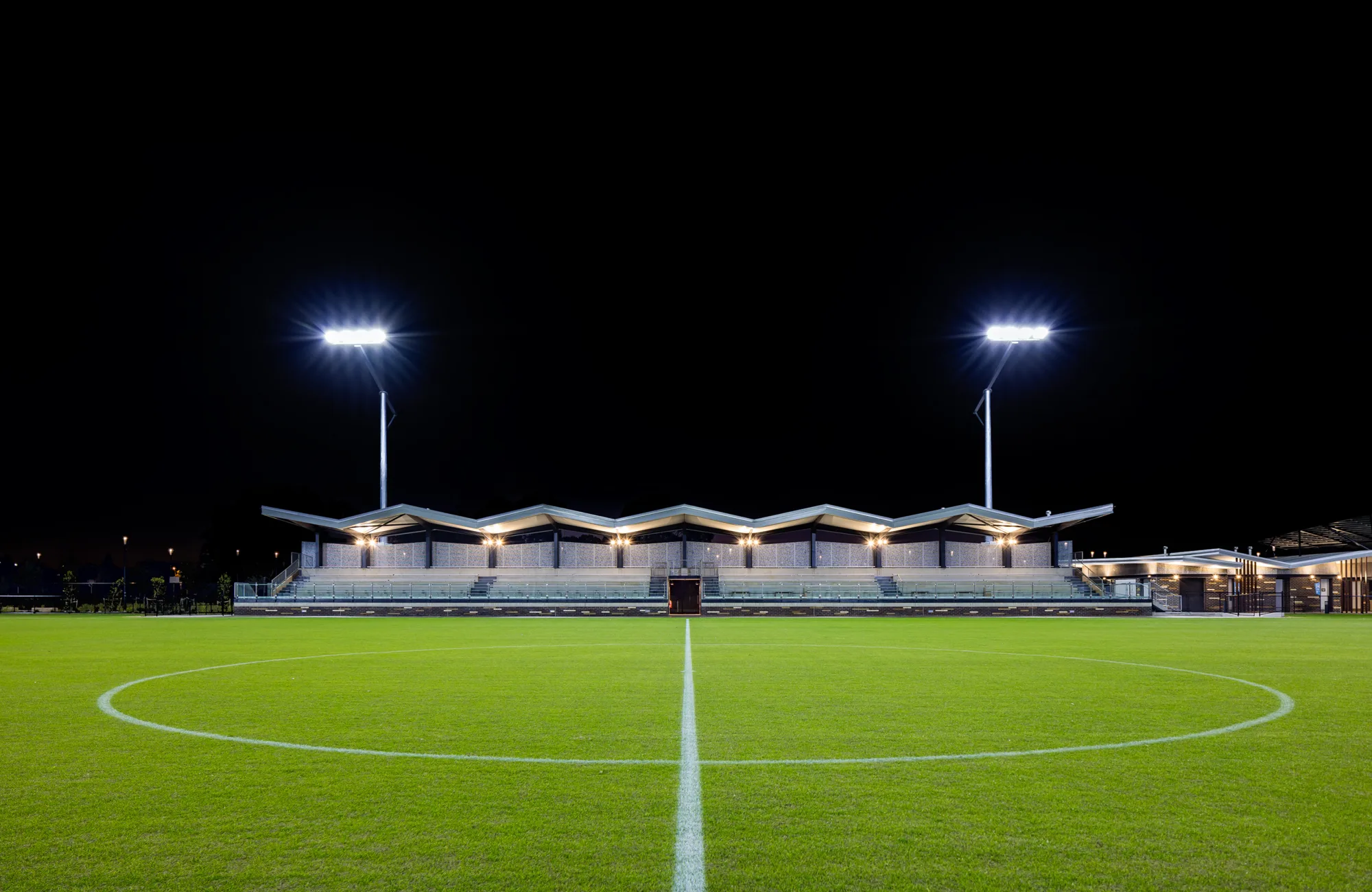 450-seat spectator grandstand at night with floodlights on.