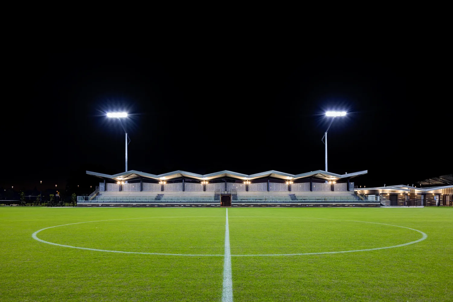 450-seat spectator grandstand at night with floodlights on.