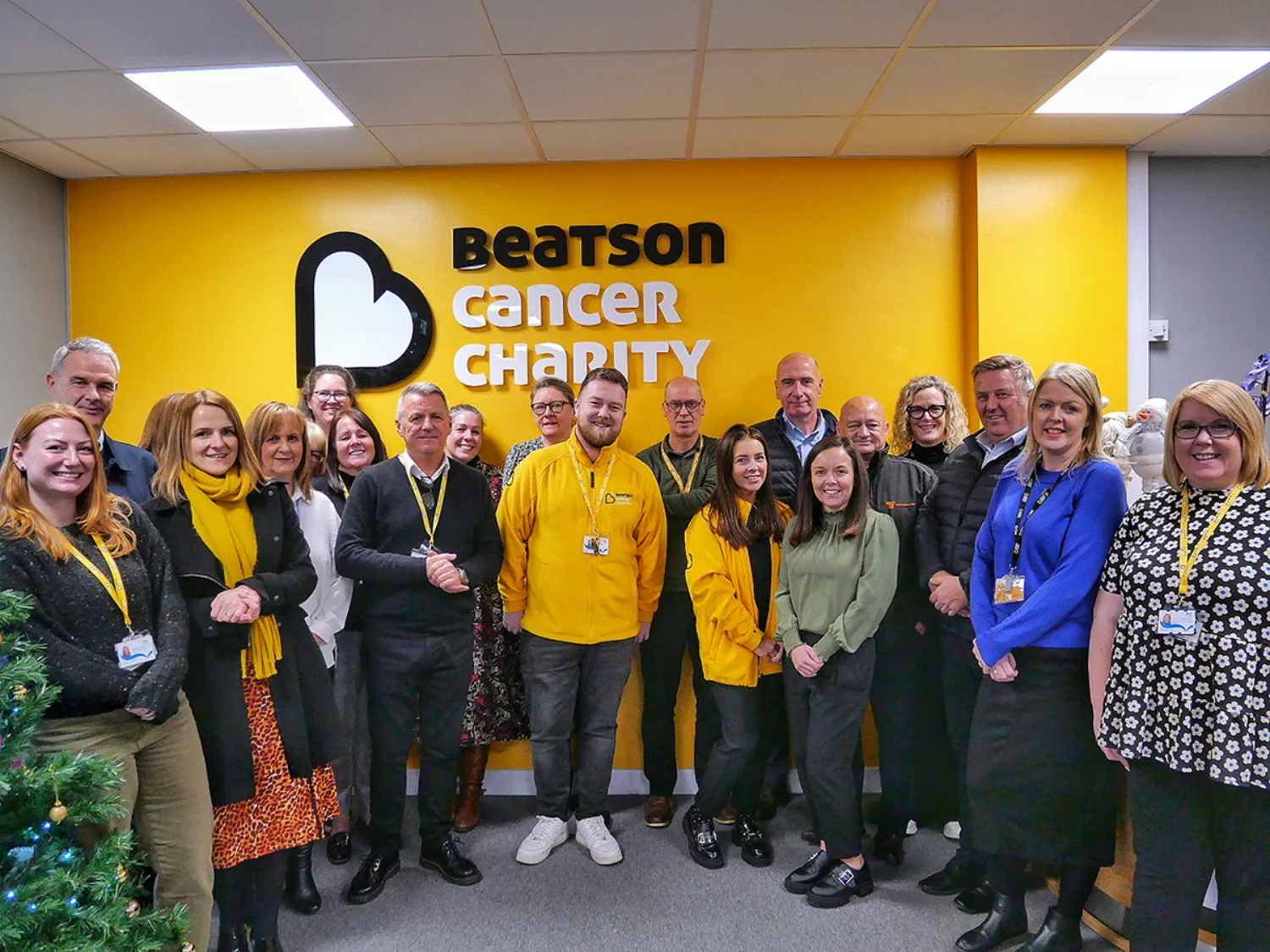 Group of people standing in front a yellow background in reception area of building