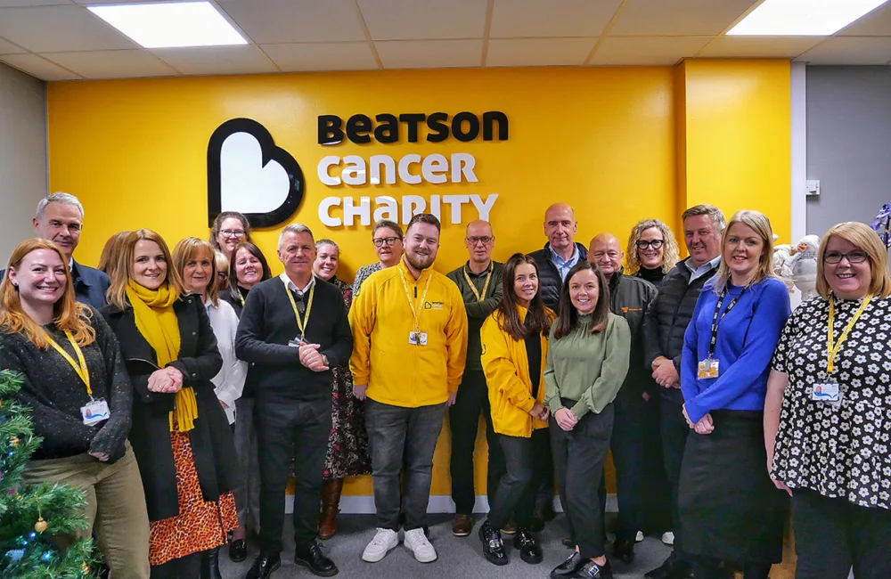 Group of people standing in front a yellow background in reception area of building