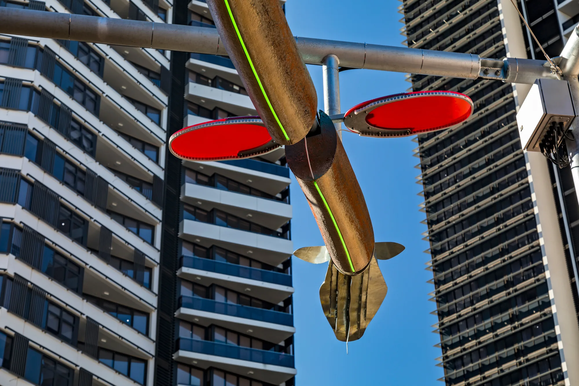 Close-up of Burra burawa structure with red in the fins; set against modern high-rise buildings in an urban environment.