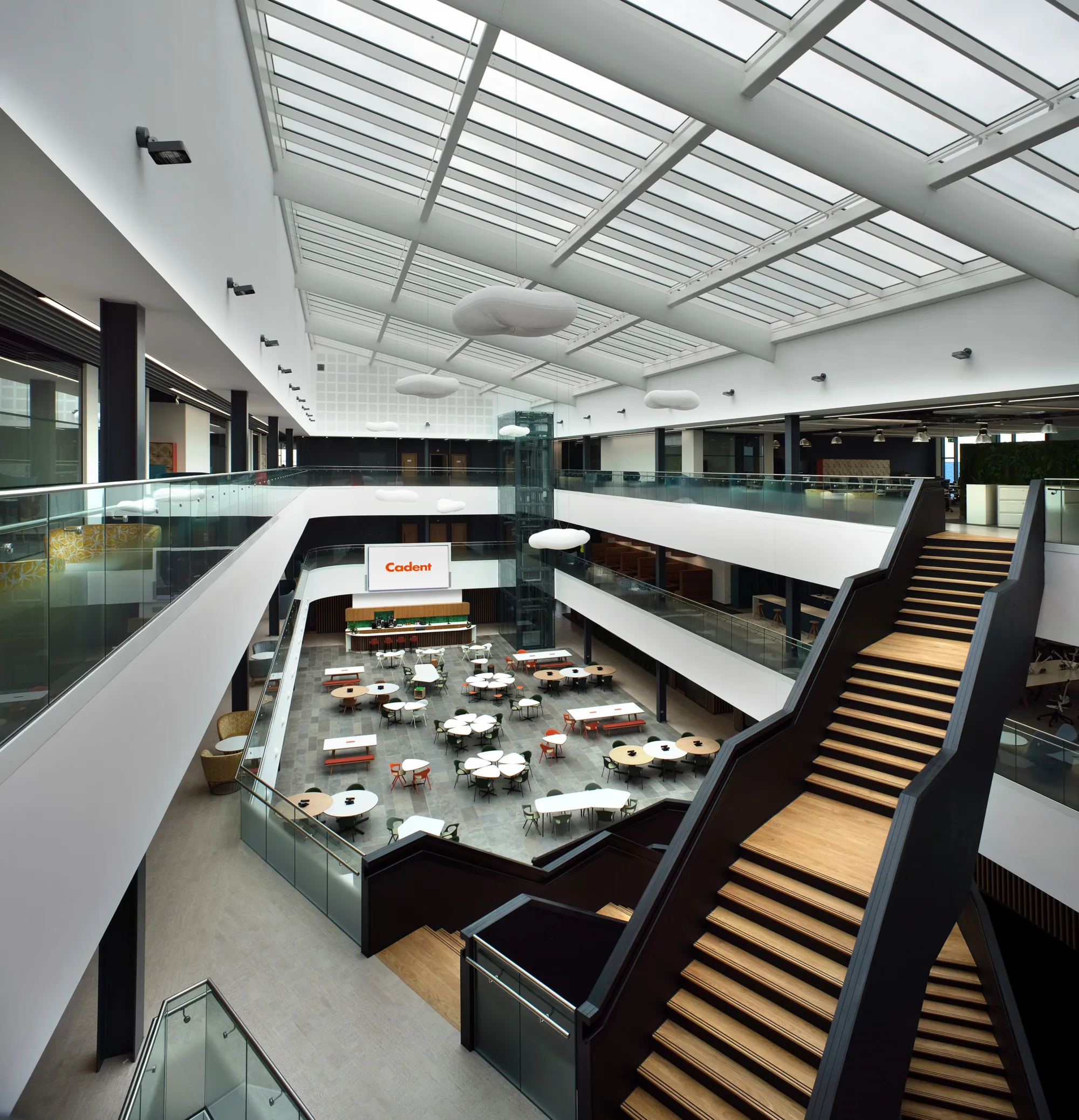 main atrium area with staircase in forground tables and chairs on ground floor, glazed ceiling, Cadent signage on far wall