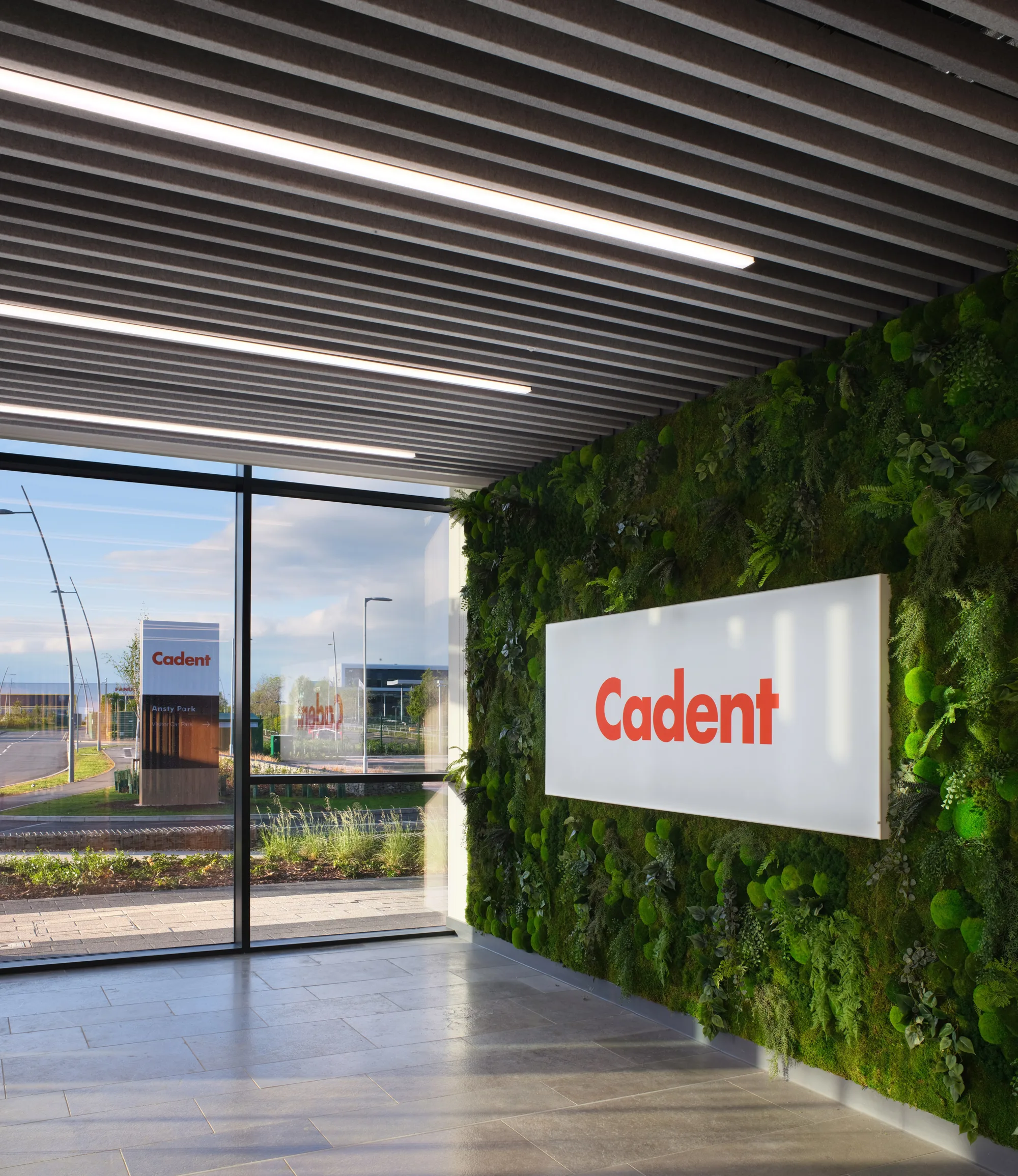 Cadent signage on green wall on right hand sign, view through window at end