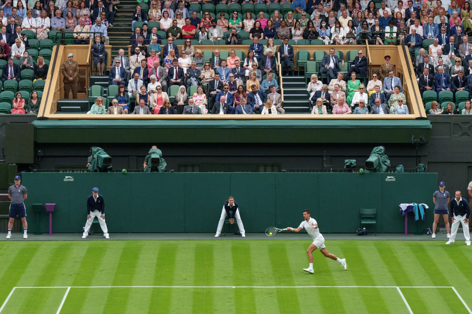 Tennis player running to hit the ball on centre court in front of spectators