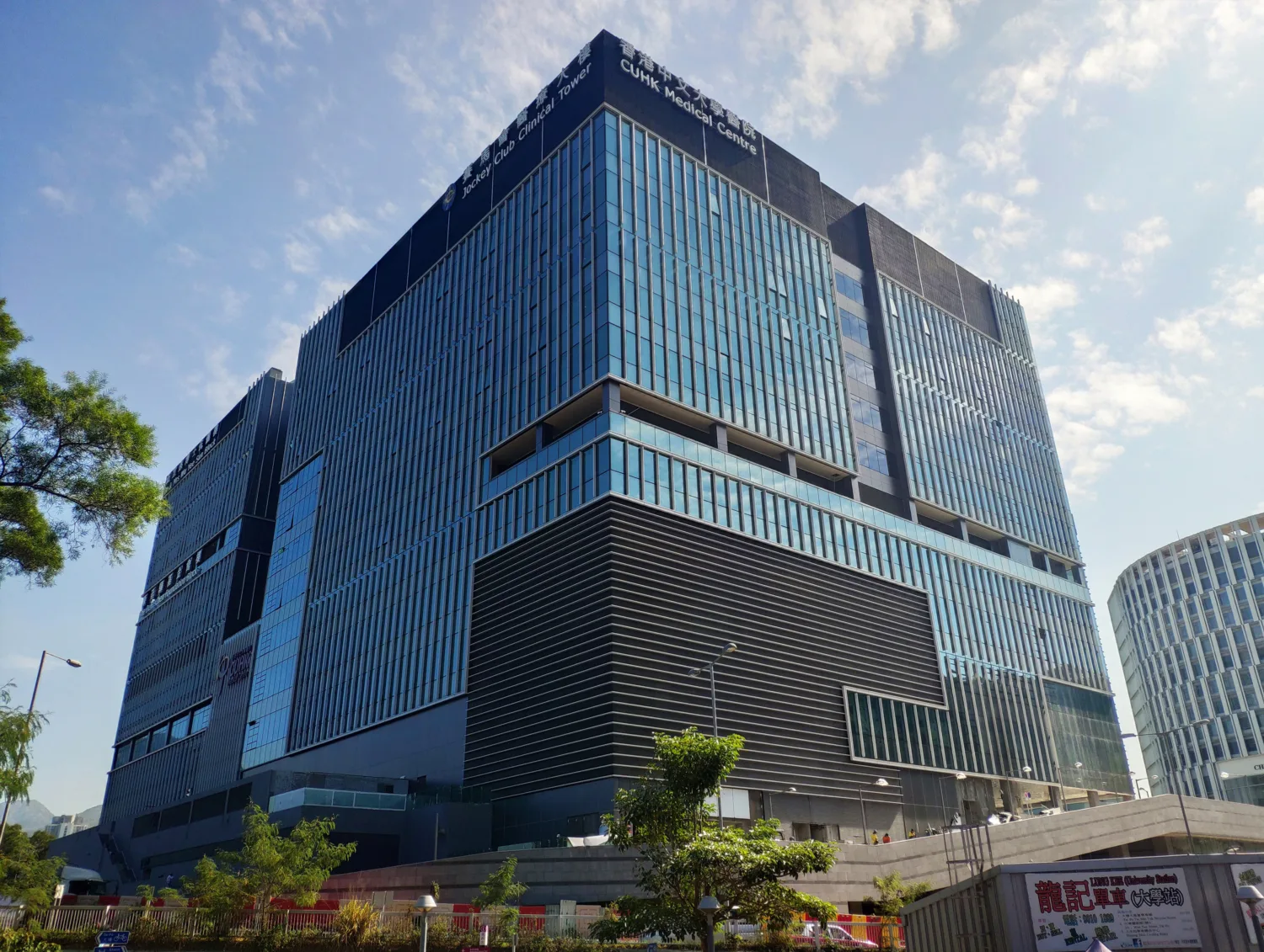 Upwards view of the building exterior with windows reflecting the blue sky