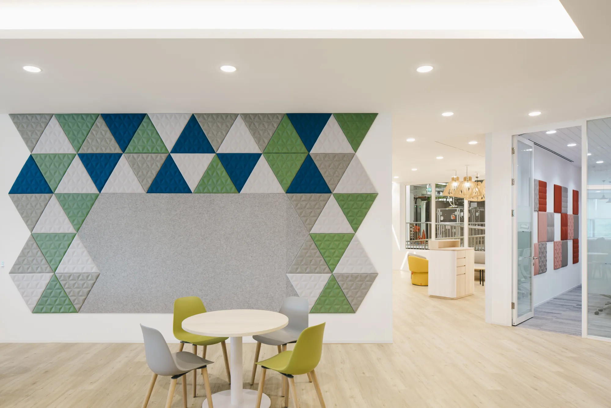 Wooden-floored open space featuring small round table with chairs in front of a geometric wallpaper