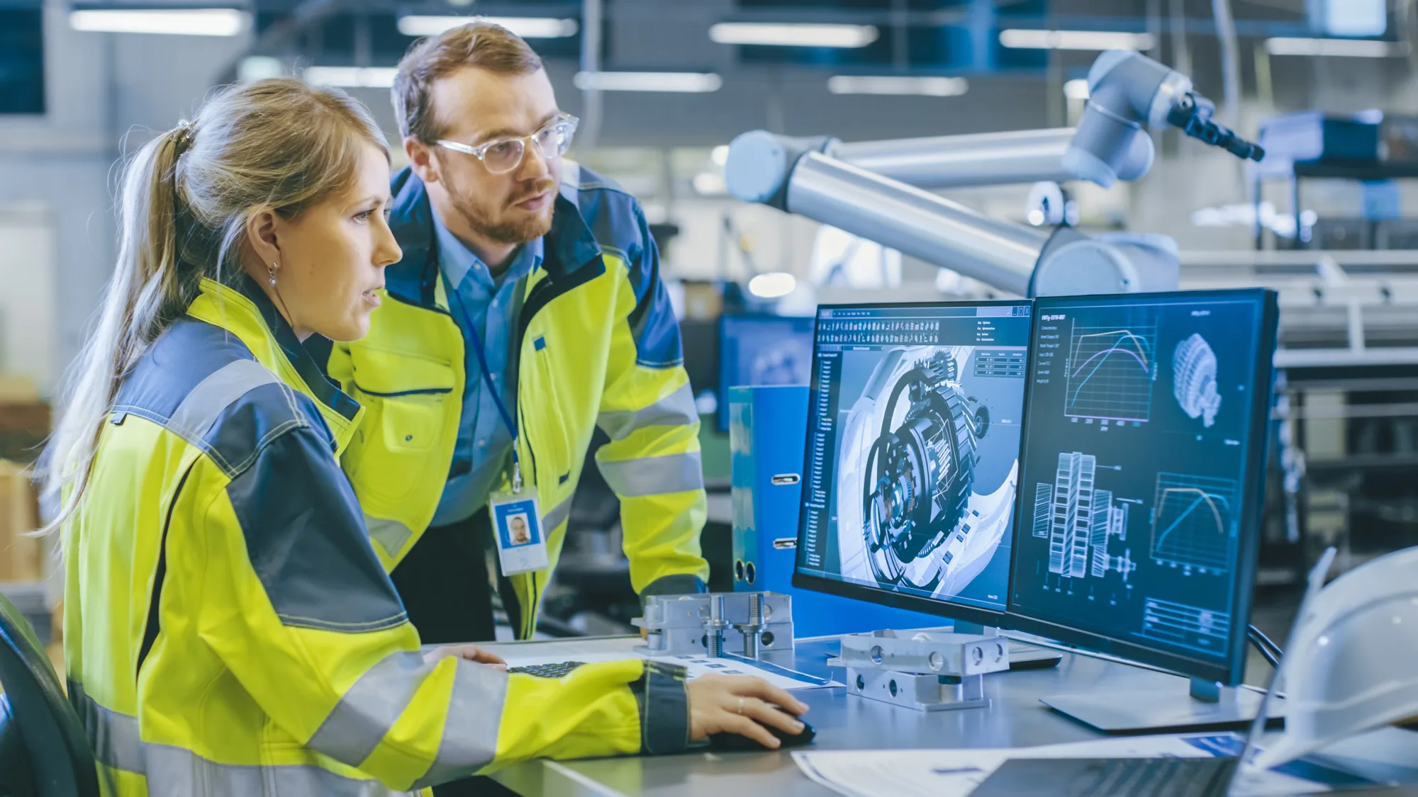 Two people in reflective jackets looking at a computer screen in a laboratory