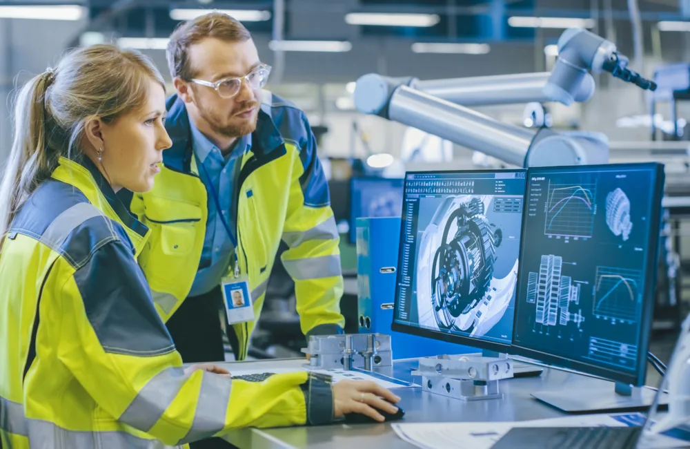 Two people in reflective jackets looking at a computer screen in a laboratory