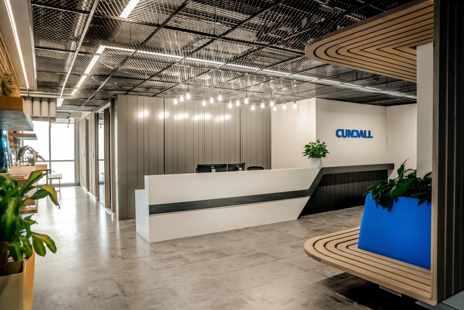 Illuminated reception area at our Cundall Dubai WELL office with plants and a cantilevered waiting seat