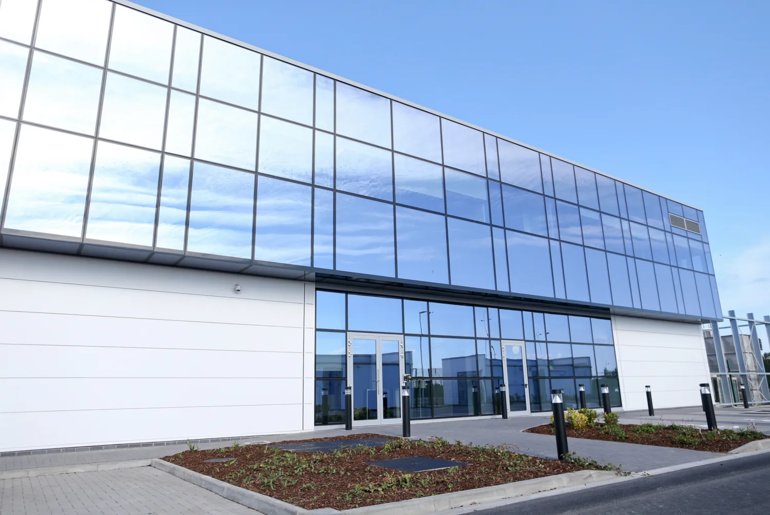 Front of building with windows reflecting the blue sky and wispy clouds