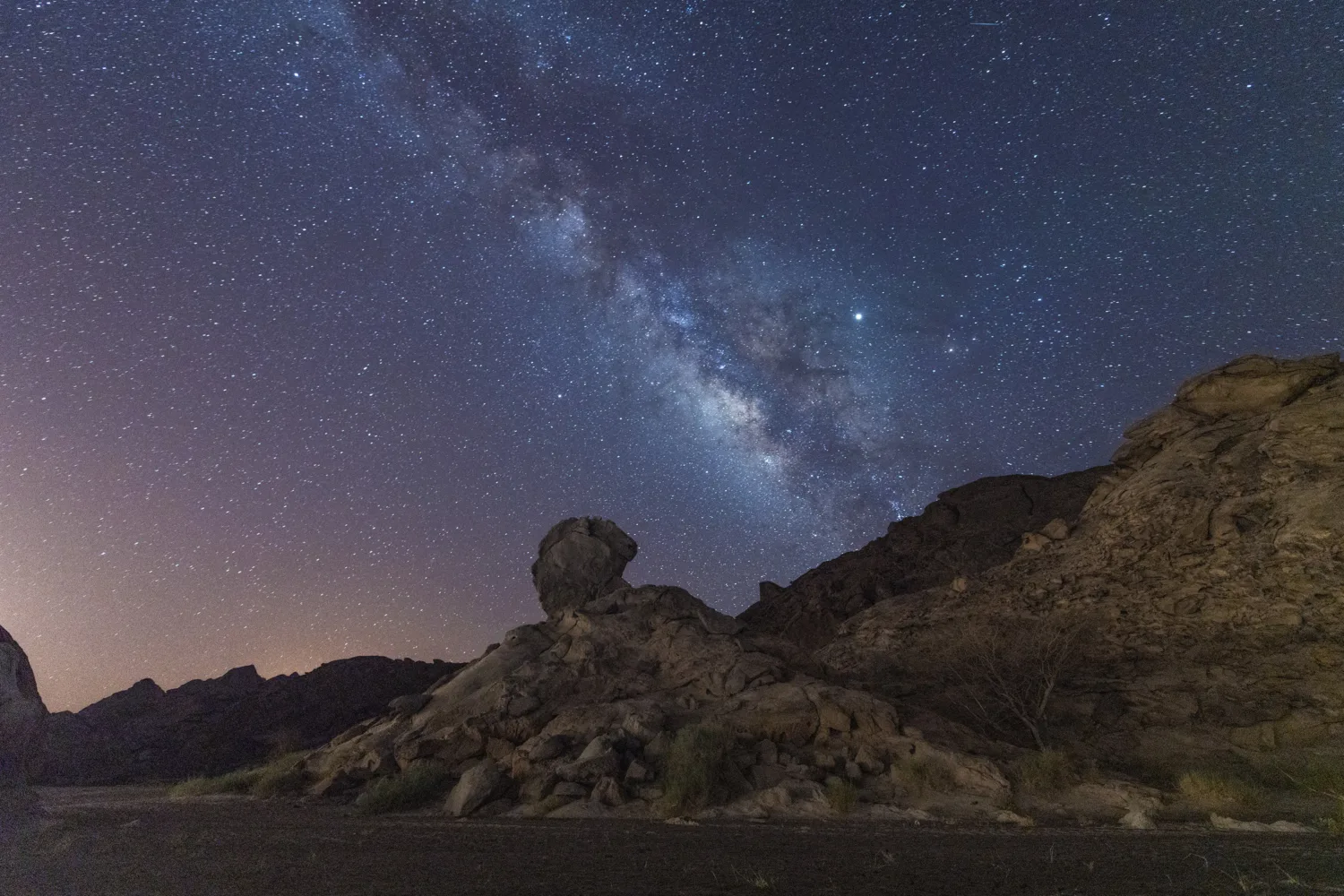 Amazing clear night shot of the milky way galaxy over a rocky hill